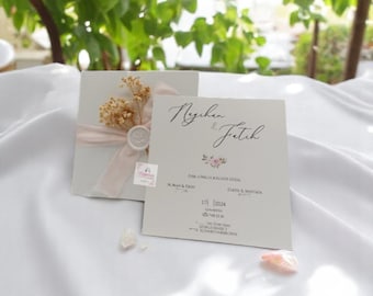 May include: A white wedding invitation with a pink ribbon and dried flowers. The invitation reads "Neyşen & Fetih" and includes the date "17.1.2024".