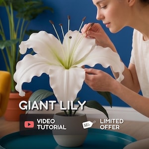 Puede incluir: Un gran lirio blanco en una maceta gris y blanca. La flor tiene acentos verdes y estambres oscuros. El texto "GIANT LILY" se muestra encima de un botón de tutorial en vídeo y una etiqueta de "LIMITED OFFER".