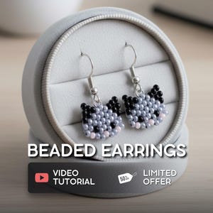 May include: A pair of beaded earrings in a gray jewelry box. The earrings are shaped like cat faces, with black and gray beads forming the head and pink beads for the cheeks. The text "BEADED EARRINGS" is displayed above the earrings.