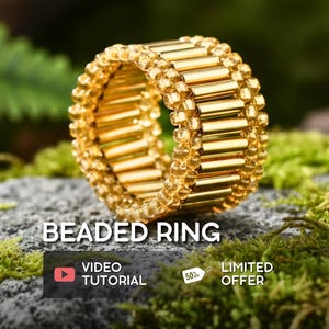 May include: A gold beaded ring with a cylindrical design. The ring is made of small, gold-colored beads and is set against a natural background of moss and stone. The text "BEADED RING" is displayed above the ring.