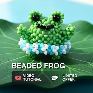 May include: A handcrafted beaded frog figurine in shades of green, black, and white, with a blue and white beaded band. The frog is displayed on a green leaf against a blue background. The text "BEADED FROG" is visible.
