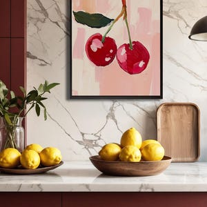 May include: A framed painting of two red cherries with green leaves on a pink background.