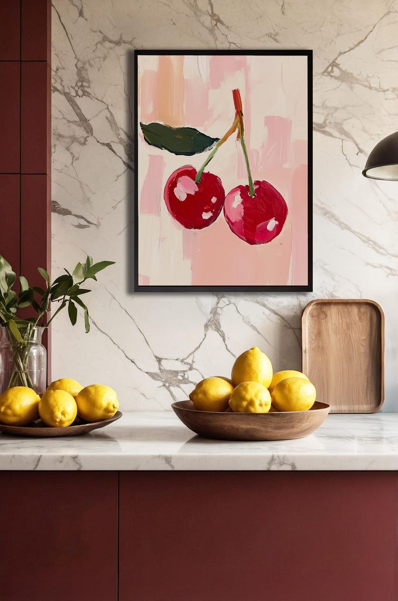 May include: A framed painting of two red cherries with green leaves on a pink background.