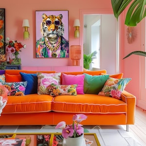 May include: A bright orange velvet sofa with colourful cushions dominates a pink-walled living room. A framed picture of a tiger wearing sunglasses is above the sofa. The room is decorated with plants and lamps.