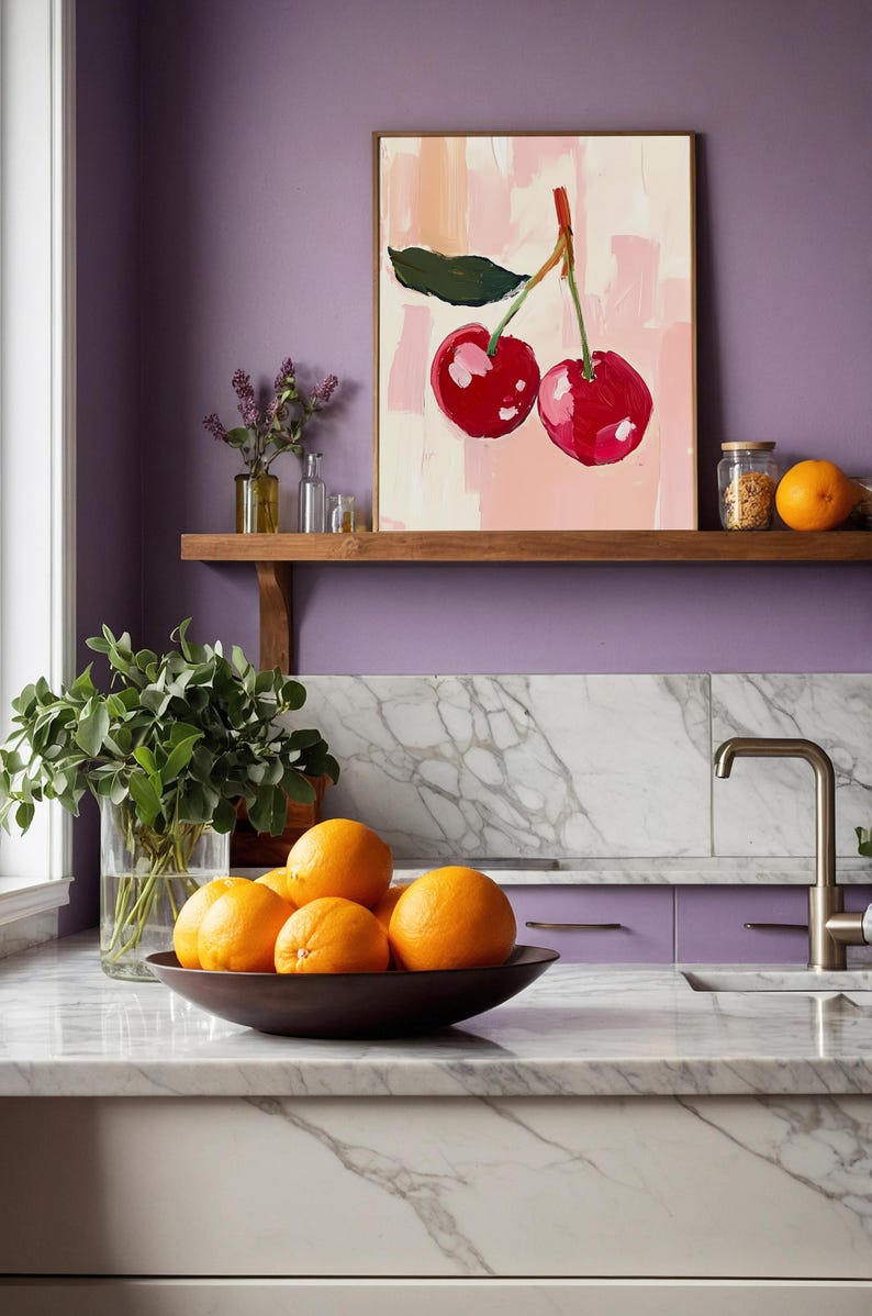 May include: A painting of two red cherries on a pink background, hanging on a shelf above a kitchen counter with a bowl of oranges. The kitchen has a purple wall and marble countertops.