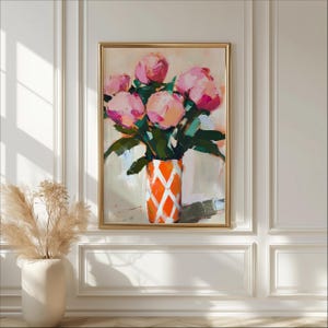 May include: An abstract painting of pink peonies in an orange vase with a white diamond pattern. The artwork is framed in a gold-colored frame and hangs on a white wall. The painting has a soft, painterly style with visible brushstrokes.