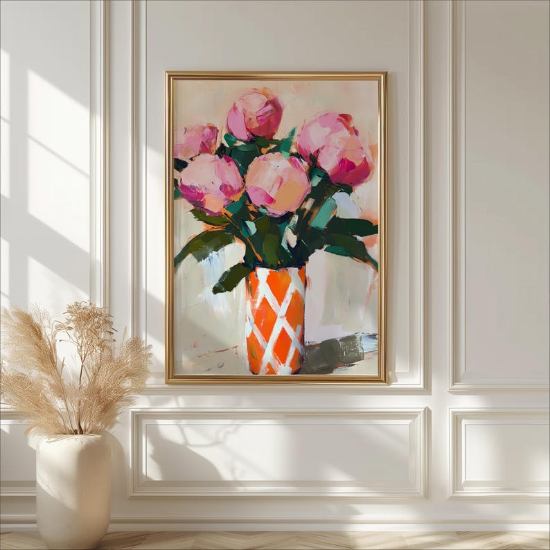 May include: An abstract painting of pink peonies in an orange vase with a white diamond pattern. The artwork is framed in a gold-colored frame and hangs on a white wall. The painting has a soft, painterly style with visible brushstrokes.