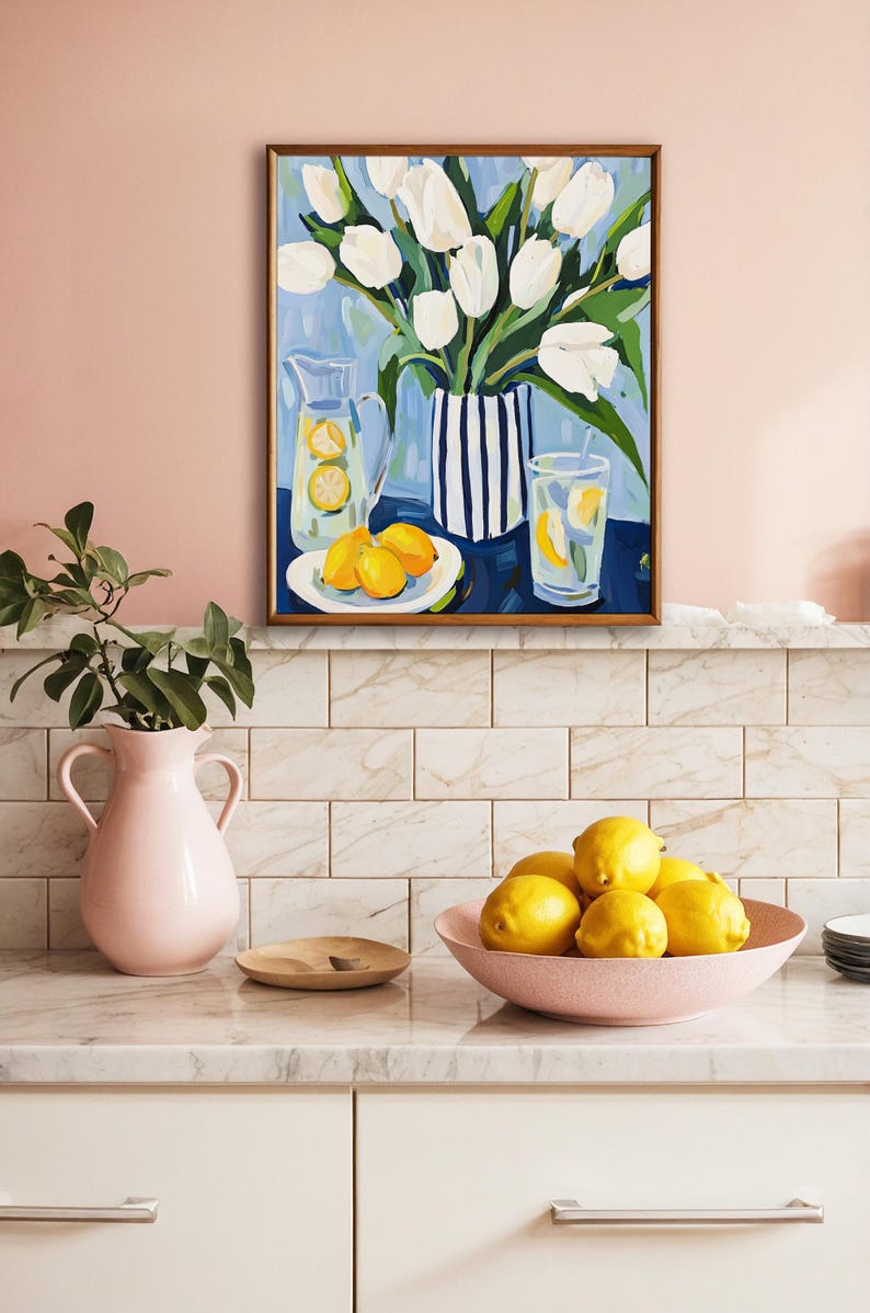 Puede incluir: Una pintura enmarcada representa tulipanes blancos en un jarr&oacute;n a rayas, con limones y limonada. Una jarra rosa y un cuenco de limones est&aacute;n sobre una encimera. La escena evoca un ambiente fresco y veraniego.