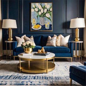 Puede incluir: Un sal&oacute;n lujoso con un sof&aacute; de terciopelo azul oscuro, acentuado por cojines decorativos y una mesa de centro redonda con tapa de m&aacute;rmol. L&aacute;mparas y mesas auxiliares doradas flanquean el sof&aacute;, con una pintura floral encima.
