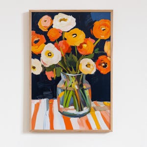 May include: A framed floral art print featuring a bouquet of orange, yellow, and white flowers in a clear glass vase. The background is a dark blue, and the table has orange and white stripes. The artwork is in a wooden frame.