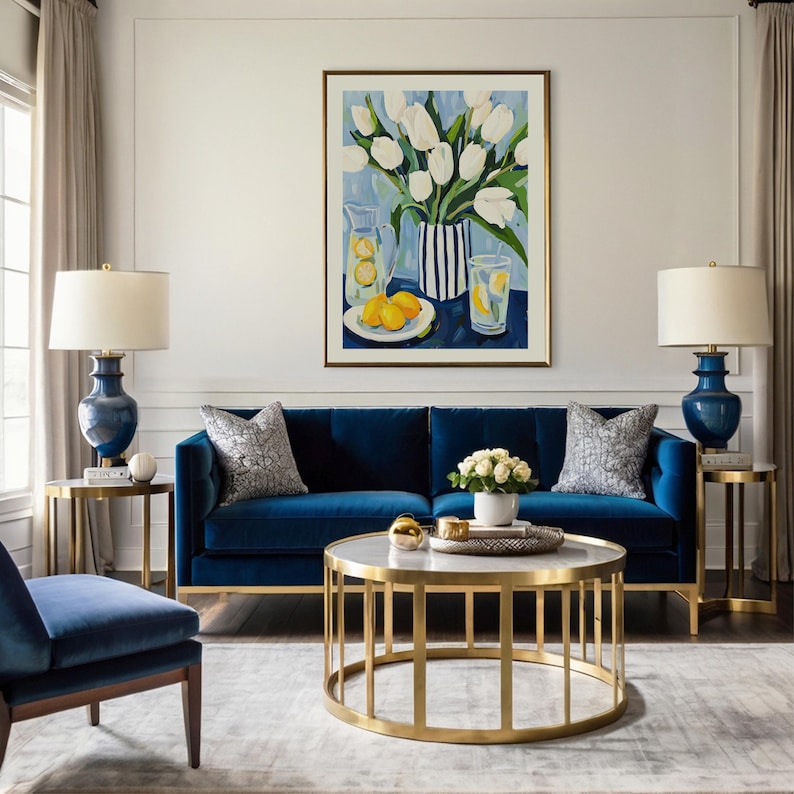 Puede incluir: Un sal&oacute;n con un sof&aacute; de terciopelo azul marino, dos l&aacute;mparas a juego y una mesa de centro con marco dorado. Una pintura de tulipanes blancos y limones cuelga sobre el sof&aacute;. La habitaci&oacute;n est&aacute; decorada con cortinas de tonos neutros y una alfombra gris.