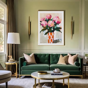 May include: An interior shot of a living room with a green velvet sofa, a marble-topped coffee table, and a framed painting of pink flowers in an orange vase. The room has gold accents and a neutral rug.