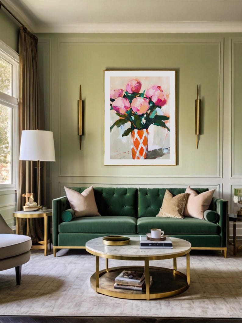 May include: An interior shot of a living room with a green velvet sofa, a marble-topped coffee table, and a framed painting of pink flowers in an orange vase. The room has gold accents and a neutral rug.