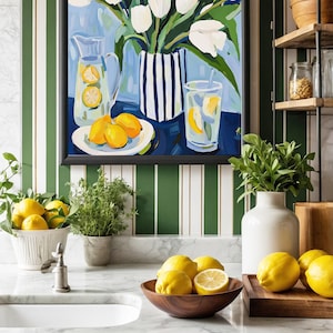 Puede incluir: Interior de cocina con un cuadro de tulipanes blancos en un jarr&oacute;n a rayas azules y blancas, una jarra y un vaso de limonada, y un plato de limones. Limones frescos en un cuenco de madera y sobre una tabla de cortar. La cocina tiene armarios verdes y encimera de m&aacute;rmol.