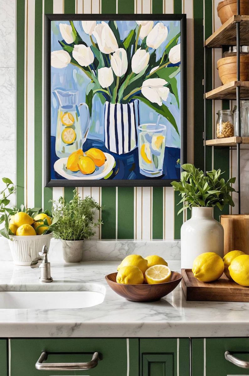 Puede incluir: Interior de cocina con un cuadro de tulipanes blancos en un jarr&oacute;n a rayas azules y blancas, una jarra y un vaso de limonada, y un plato de limones. Limones frescos en un cuenco de madera y sobre una tabla de cortar. La cocina tiene armarios verdes y encimera de m&aacute;rmol.
