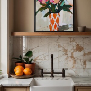 May include: An abstract painting of pink flowers in an orange and white patterned vase. The painting is framed and displayed above a kitchen sink with oranges and potted plants.