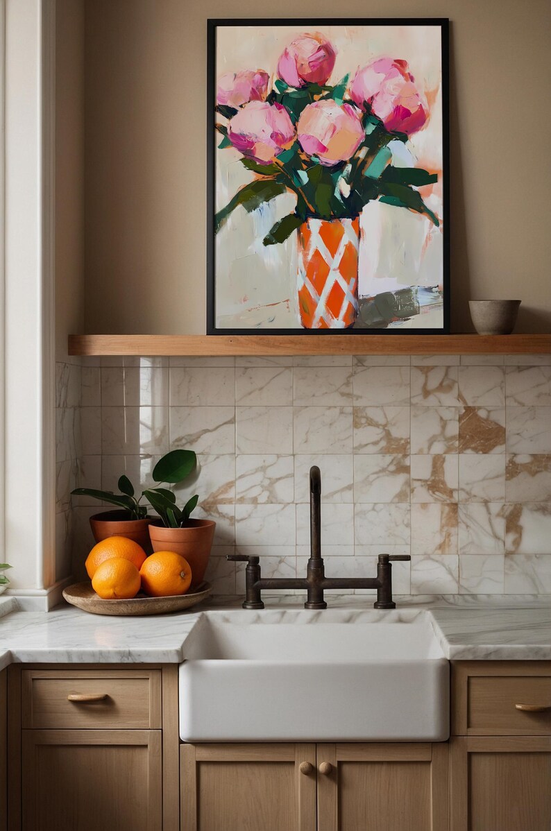 May include: An abstract painting of pink flowers in an orange and white patterned vase. The painting is framed and displayed above a kitchen sink with oranges and potted plants.