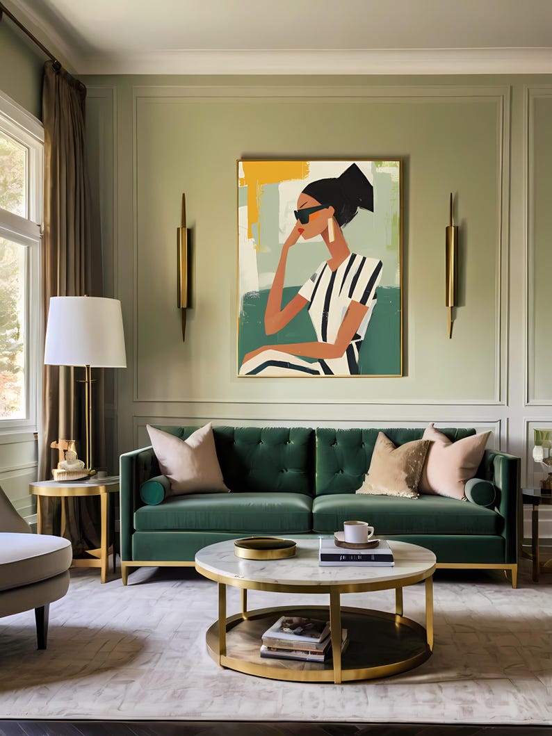 May include: A green velvet sofa with gold accents sits in a living room with a coffee table and a painting of a woman wearing sunglasses and a striped shirt. The painting is framed in gold and has a green background.