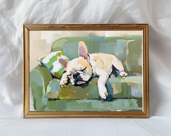 May include: A framed painting of a cream-colored French Bulldog sleeping on a green sofa. The dog is positioned on the left side of the couch next to a green and white striped pillow. The artwork is enclosed in a thin, metallic gold-colored frame.