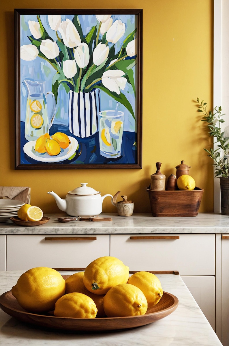 Puede incluir: Una pintura enmarcada de tulipanes blancos en un jarr&oacute;n a rayas, una jarra y un vaso de limonada con limones. Una tetera blanca, un cuenco de madera con limones y otros art&iacute;culos de cocina est&aacute;n sobre la encimera. La combinaci&oacute;n de colores es amarillo, blanco y azul.