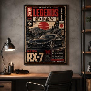 Puede incluir: Un póster enmarcado que muestra un coche deportivo Mazda RX-7 FD3S negro en una carretera sinuosa con un sol rojo y montañas de fondo. El texto incluye "LEGENDS", "DRIVEN BY PASSION", "MAZDA RX-7" y "FD3S" junto con caracteres japoneses y datos.