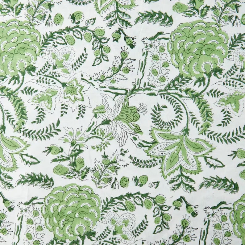 May include: A white fabric with a green floral pattern. The pattern features leaves, flowers, and vines.