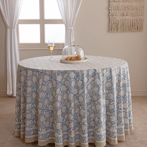 Pu&ograve; includere: Una tovaglia rotonda con un motivo floreale blu e bianco. La tovaglia &egrave; su un tavolo rotondo. Una cupola di vetro con pasticcini e un bicchiere di vino sono sul tavolo. La tovaglia ha un bordo a fantasia.