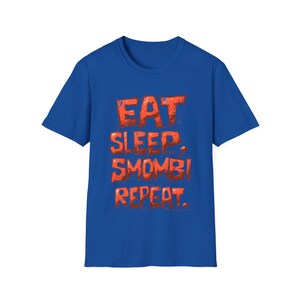 Könnte beinhalten: Ein königsblaues T-Shirt mit dem Text "EAT SLEEP SMOMBI REPEAT" in Rot.