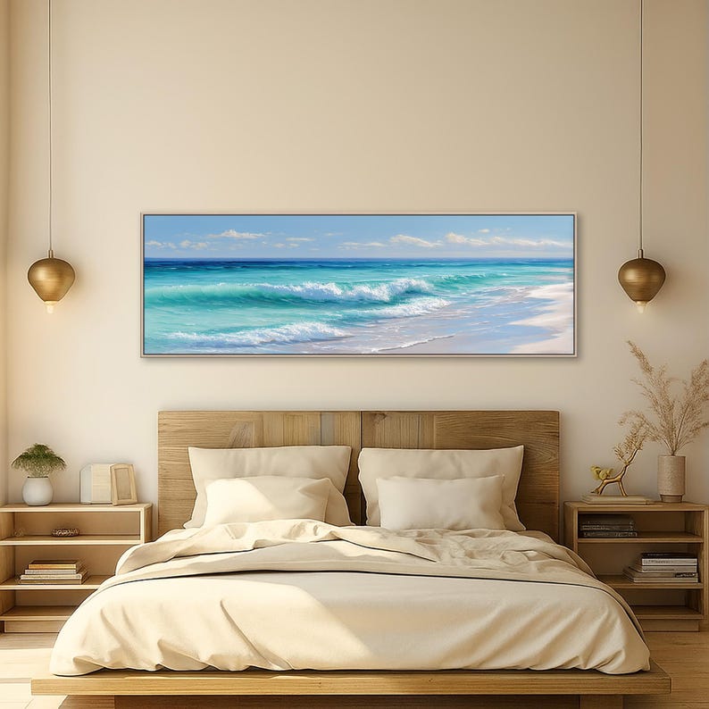 May include: A framed rectangular canvas art piece depicting a coastal scene. The artwork showcases turquoise waves crashing onto a white sandy beach under a blue sky with scattered clouds. The painting is displayed above a wooden bed frame.