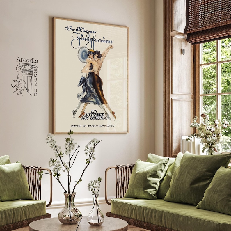 Op de afbeelding: Een ingelijste vintage poster getiteld Die Klingen Jungfrauen met een illustratie van twee dansende figuren in elegante kleding. Het kunstwerk bevat de tekst Ein Sittenbild aus Berlin.W. en Verlegt bei Wilhelm Borngr&auml;ber in een cr&egrave;mekleurige lijst.