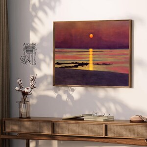 May include: A framed painting of a sunset over a body of water. The sun is a bright orange and the sky is a deep purple. The water is a light blue and there are some rocks in the foreground.