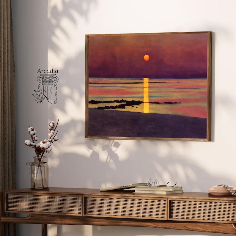 May include: A framed painting of a sunset over a body of water. The sun is a bright orange and the sky is a deep purple. The water is a light blue and there are some rocks in the foreground.