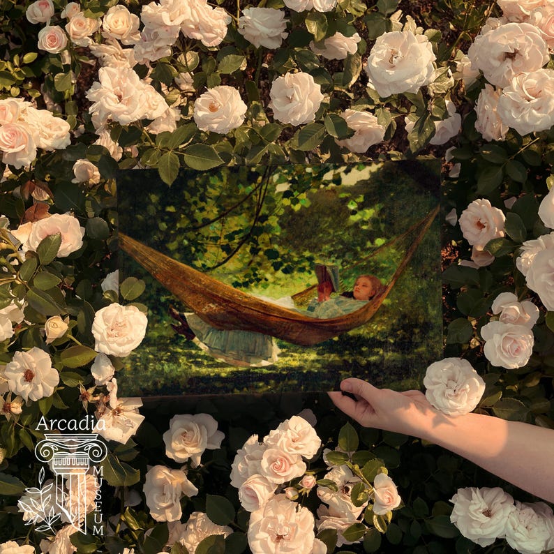 May include: A rectangular art print depicting a person reading a book while resting in a hammock suspended between trees, held against a backdrop of numerous pale pink roses. The print features a logo with the text Arcadia and a column icon.