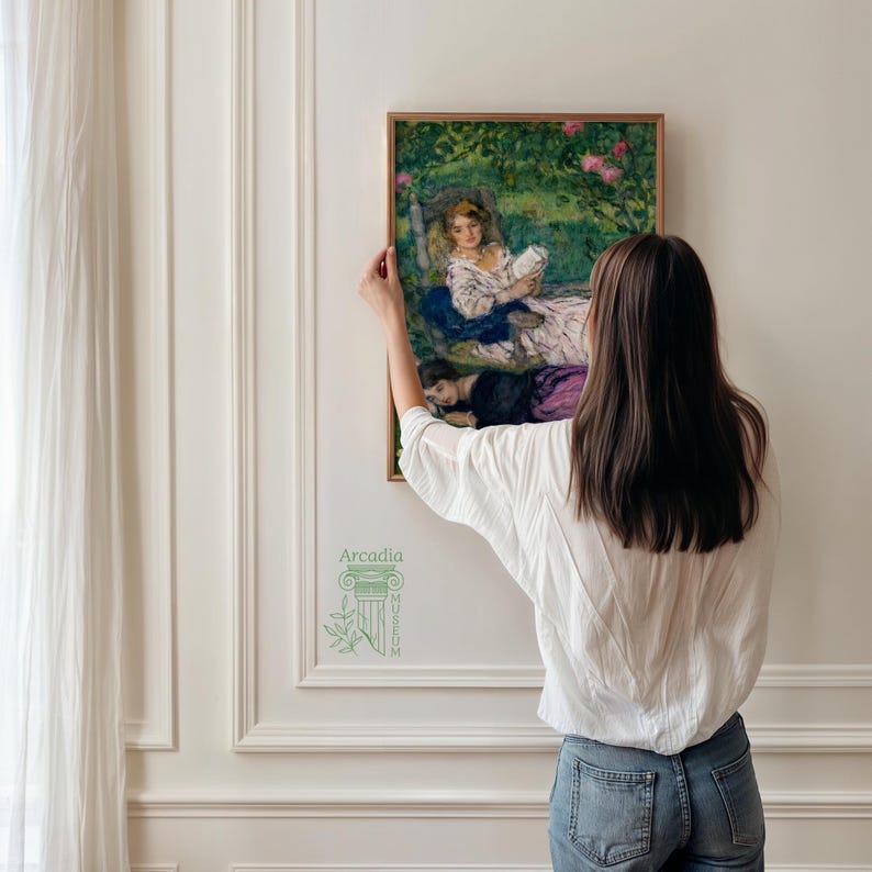 May include: A framed rectangular painting depicting two figures in a garden setting, one seated reading a book and the other lying down, rendered in impressionistic brushstrokes with green foliage and pink flowers, featuring the Arcadia Museum logo.