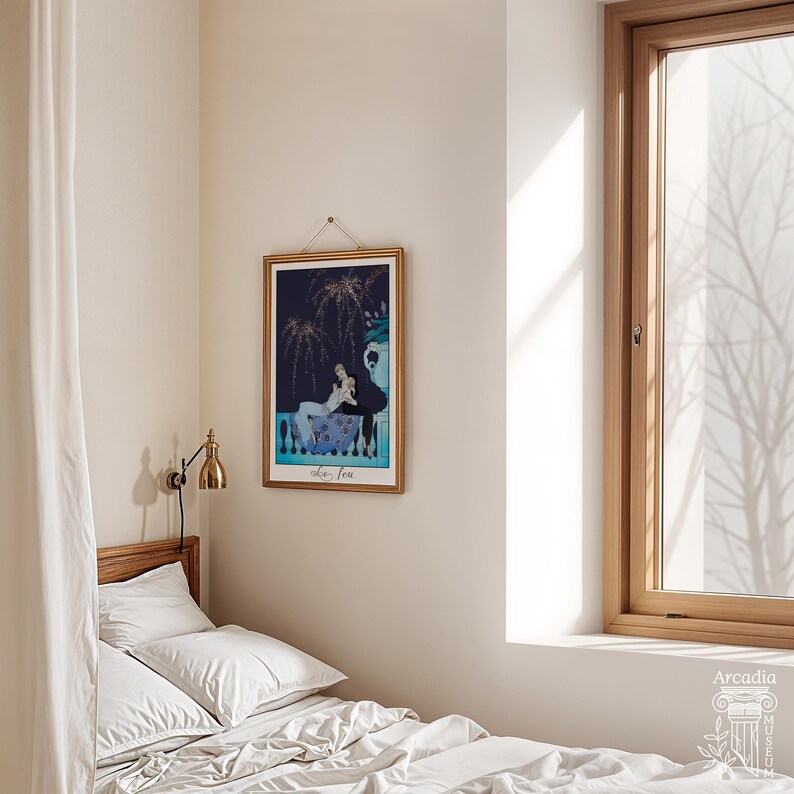 May include: A rectangular framed art print featuring a dark blue night scene with fireworks and two figures resting on a balcony. The print includes the text "Le Feu" at the bottom and is displayed in a thin gold frame with a hanging cord.