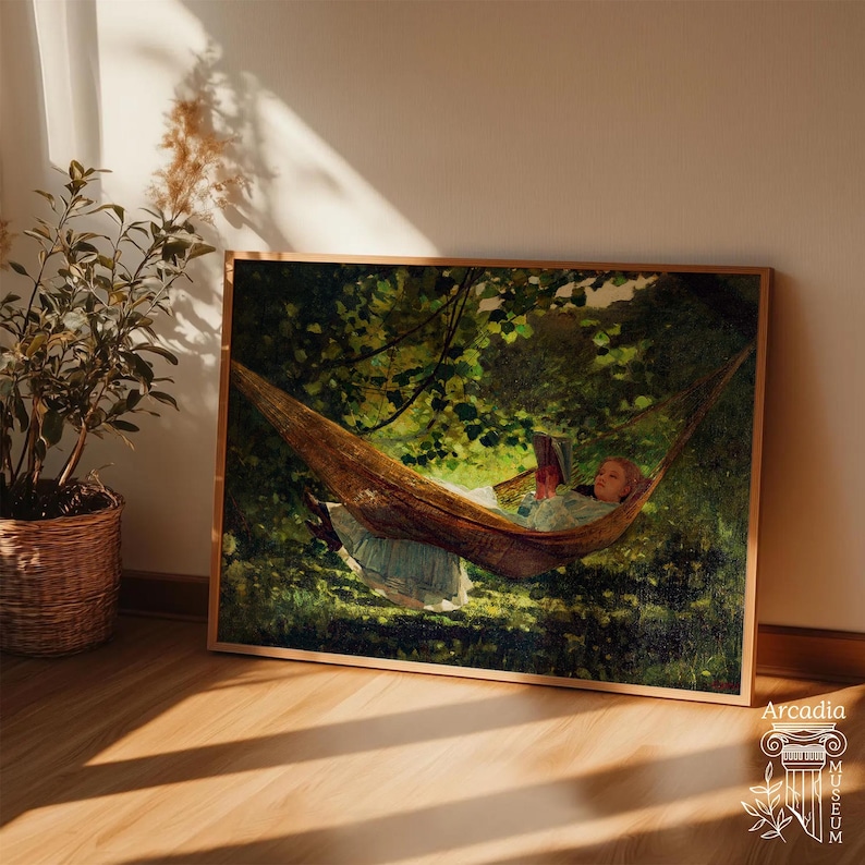 May include: A framed rectangular art print depicting a person lying in a brown hammock suspended between trees in a lush green forest. The person is wearing a light-coloured dress and reading a book. The scene features dappled sunlight.