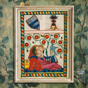 May include: A framed medieval manuscript illustration featuring a couple beneath a flowering tree with red blossoms and a blue bird. The scene includes a shield, a helmet crest, and a decorative border with diagonal red, blue, and gold stripes.