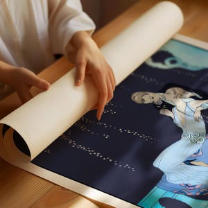 May include: A rolled-up poster featuring a dark blue background with a stylized illustration of two figures in light blue and white attire. The artwork includes delicate white dotted patterns and floral accents, presented on a smooth, cream-colored paper roll.