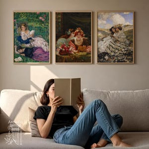 May include: Three framed rectangular wall art prints featuring classical oil paintings of figures reading in outdoor and indoor settings, displayed above a beige sofa. The artwork depicts scenes with soft colour palettes, detailed clothing, and natural light.