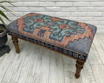 May include: A wooden bench with turned legs upholstered in a colorful patterned fabric. The fabric features a geometric design in shades of blue, green, orange, and pink.