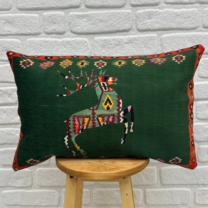 May include: Green cushion with a colourful deer design. The cushion has a red, yellow and green border.