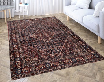 Puede incluir: Una alfombra persa tradicional con fondo azul oscuro y intrincados patrones en rojo, crema y azul. La alfombra tiene un centro en forma de diamante con un diseño floral.