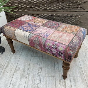 Puede incluir: Un banco de madera con patas torneadas y un cojín de patchwork hecho de tela colorida con patrones florales y geométricos.