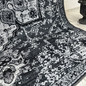 May include: A black and white area rug with a distressed, vintage look. The rug has a geometric pattern with a faded, worn appearance.