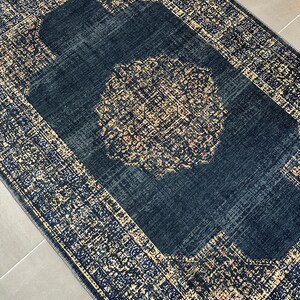 May include: A navy blue rug with a gold and cream patterned border and a large, intricate gold and cream medallion in the center.