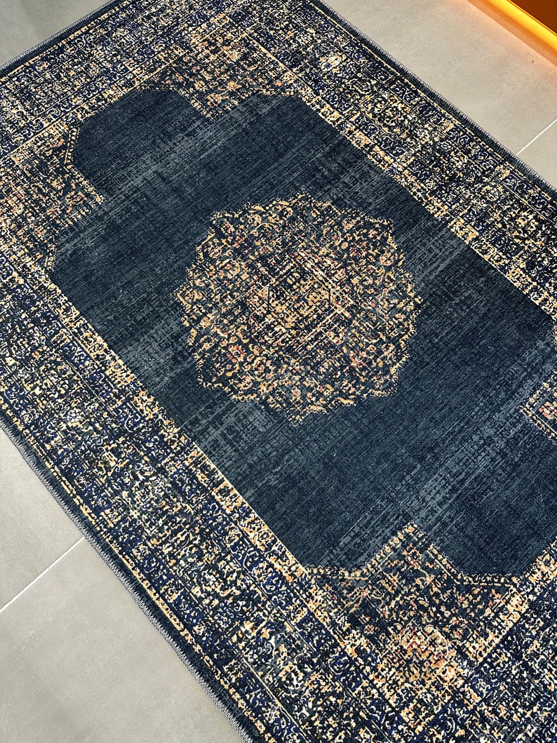 May include: A navy blue rug with a gold and cream patterned border and a large, intricate gold and cream medallion in the center.