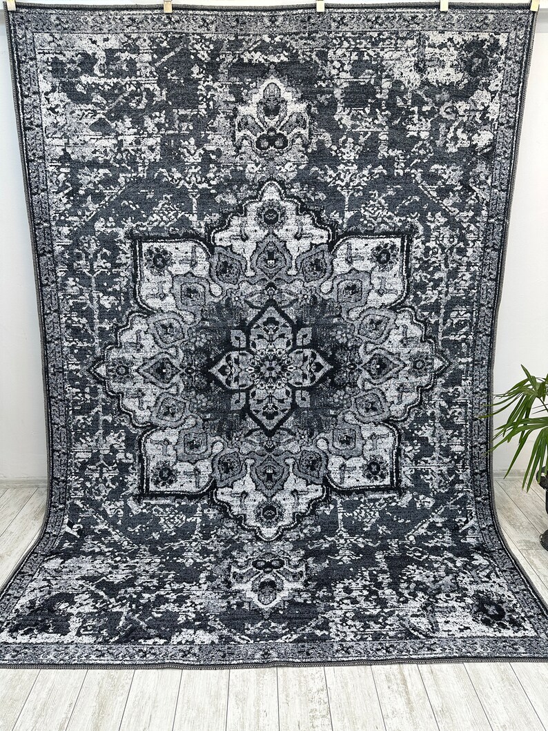 May include: A black and white area rug with a distressed, vintage look. The rug features a large, intricate medallion design in the center.