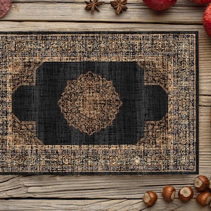 Può includere: Un tappeto con motivo nero e dorato con un design geometrico. Il tappeto è su una superficie di legno con decorazioni autunnali.