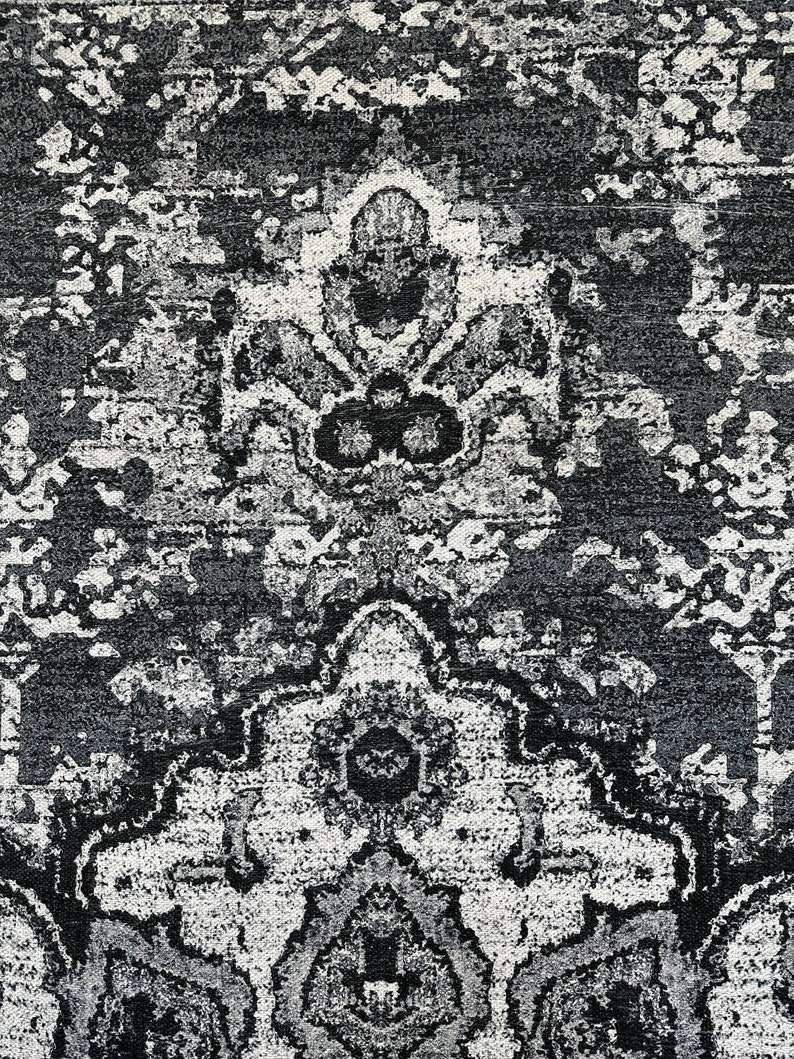 May include: Black and white area rug with a traditional Persian design. The rug has a distressed look and features intricate floral patterns.