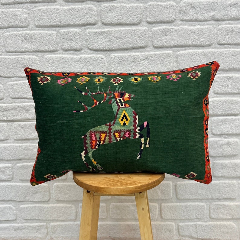May include: Green cushion with a colourful deer design. The cushion has a red, yellow and green border.